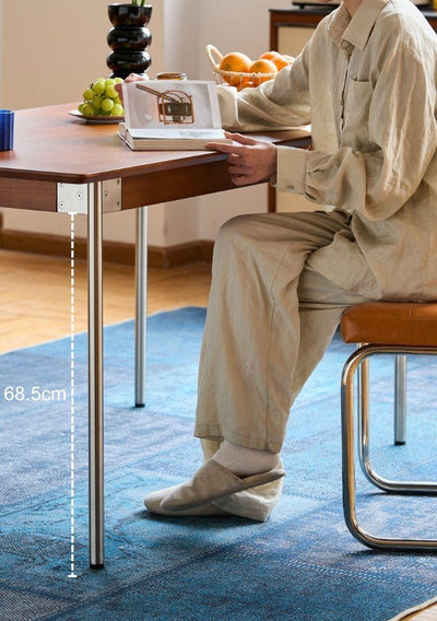 Person sitting at a table with a laptop, measuring the table's height.