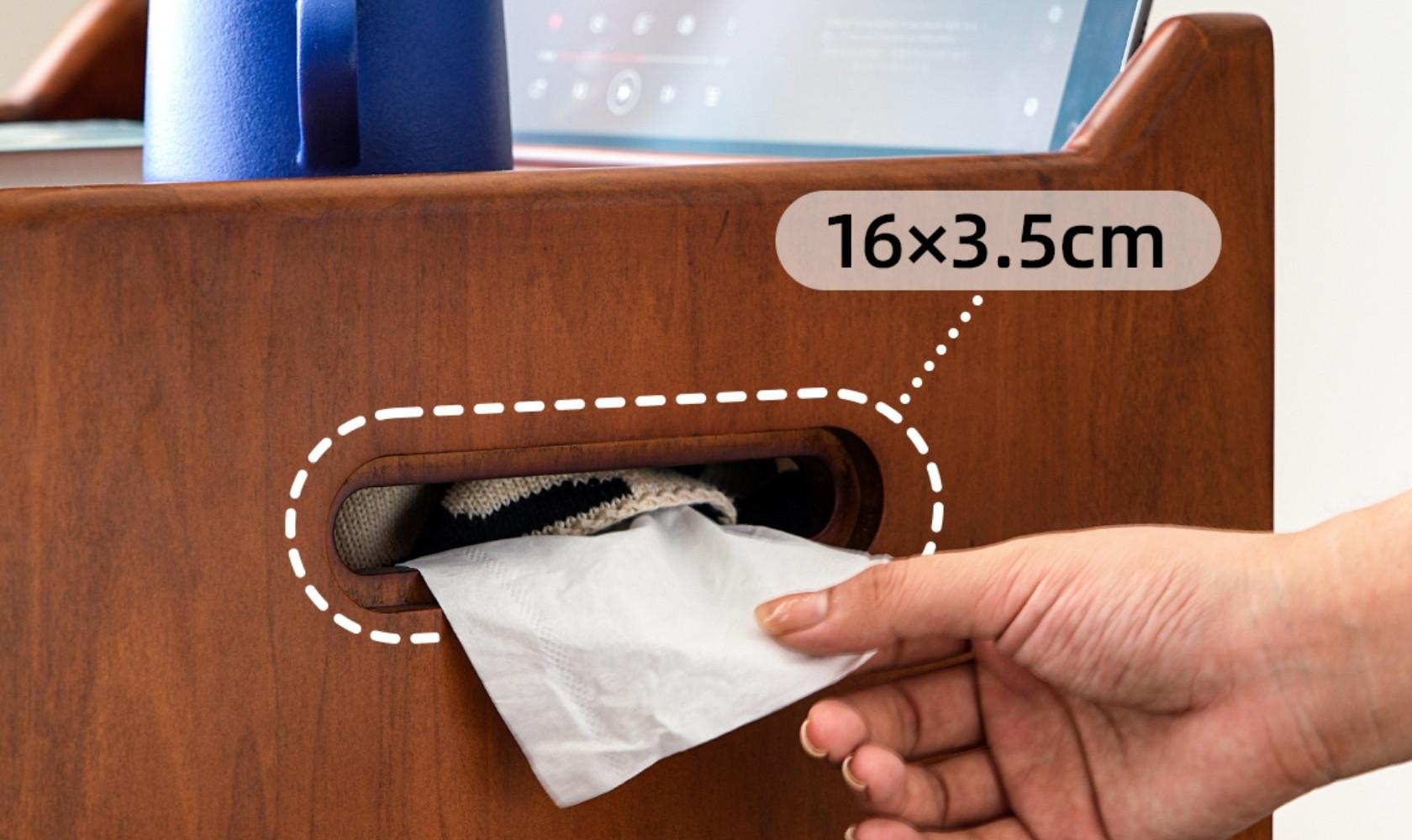 Hand placing a small white paper towel into a wooden cabinet with dimensions displayed.