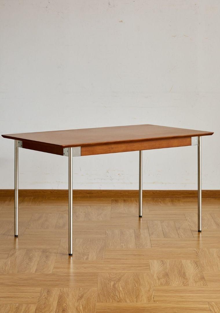 Wooden table with metal legs on a wooden floor against a white wall