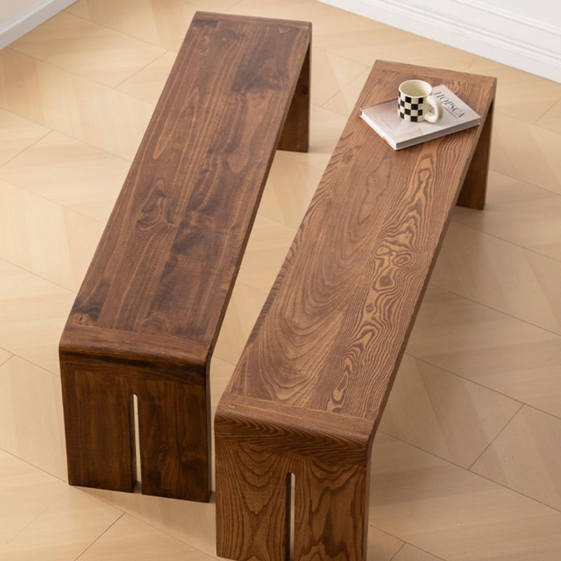 Two wooden benches on a tiled floor with a cup and book on one of them.